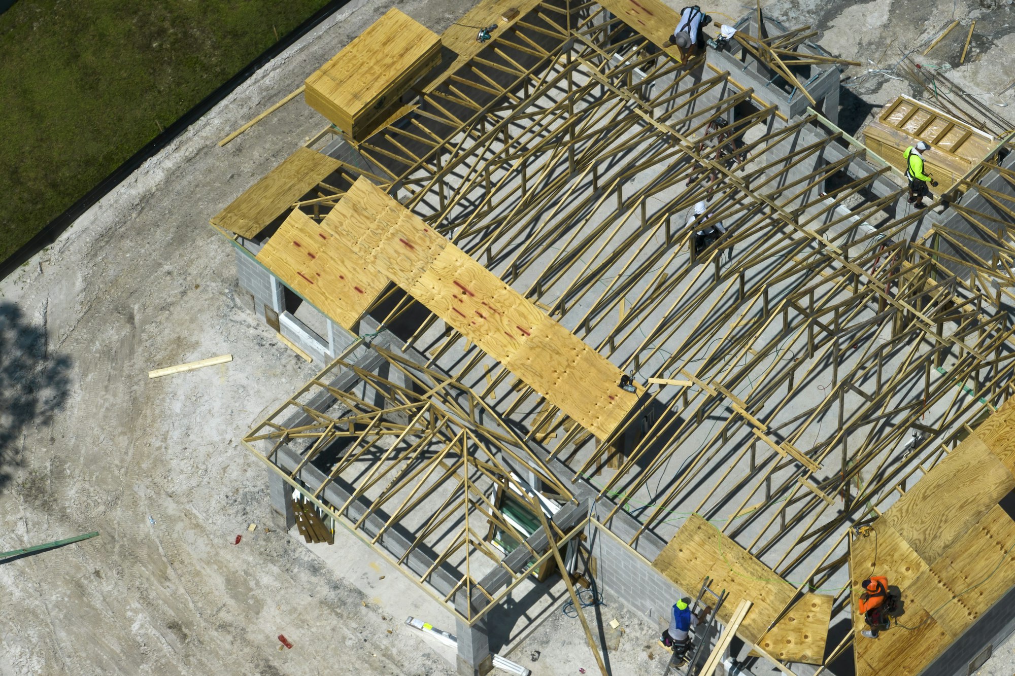 Professional builders working on roof construction of unfinished suburban home